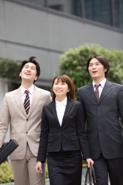 İş adamları ofis binasının yanında yürüyorlar.