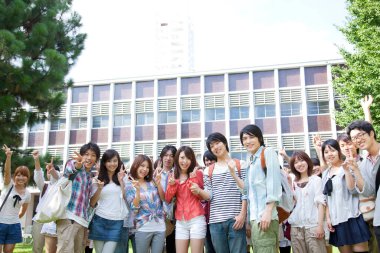 Asyalı mutlu üniversite öğrencileri üniversitenin yakınında poz veriyorlar.