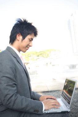 Dizüstü bilgisayar kullanan takım elbiseli bir adam.