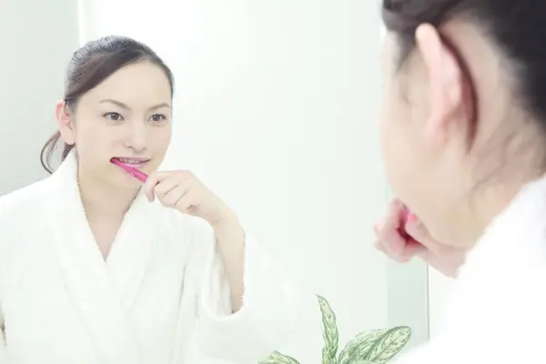 young asian woman in bathrobe with toothbrush