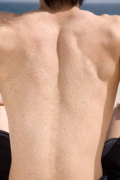 cropped photo of young man back with sand on beach