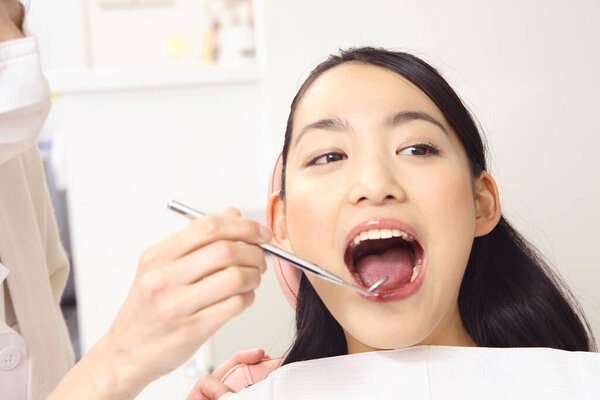 young asian  woman getting her teeth treatment at dentist office 