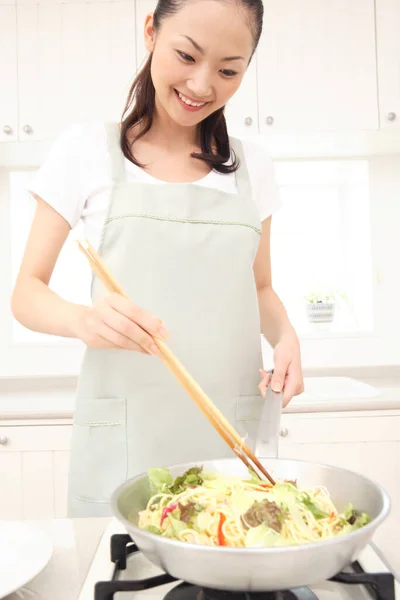 beautiful Asian housewife cooking in kitchen