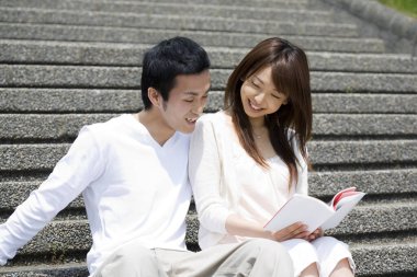 Asyalı üniversite öğrencileri basamaklarda okuyor. 