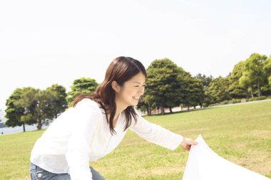 Parkta beyaz çarşaf tutan güzel Japon kadın.