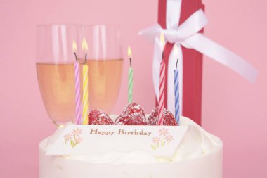 Mumlu doğum günü pastası ve taze çilekler ve şampanya ile bardaklar.