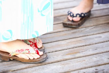 Ahşap güvertede renkli terlikler giyen ayaklar.