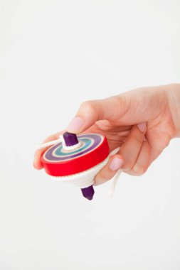 Kadın eli ahşap dönen klasik oyuncağı tutuyor. Beyaz arkaplanda girdap oyuncağı