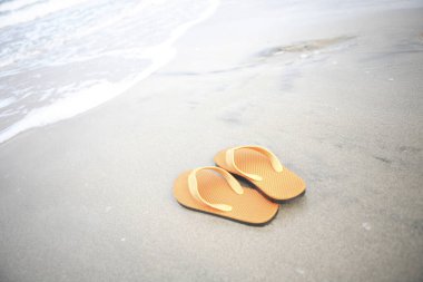 Kumlu sahilde sarı flip flop 