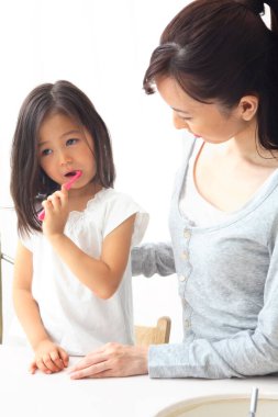 Anne ve kızı dişlerini fırçalıyor.