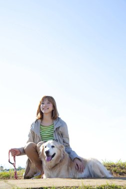 Parkta av köpeğiyle gezen güzel genç Japon kadın.