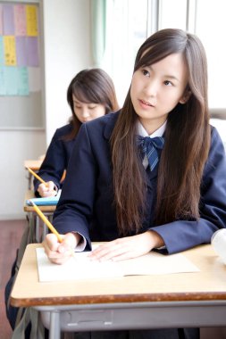 Öğrenciler sınıftaki masalarda yazı yazıyor