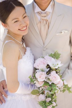 Dışarıda poz veren mutlu Asyalı bir çift yeni evli.