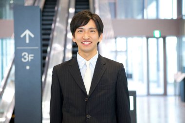 Takım elbiseli bir adam yürüyen merdivenin önünde duruyor.