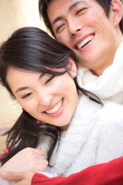 Çift evde sarılıyor, gülümsüyor.