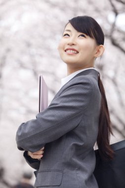 Sakura 'nın çiçek açma mevsiminde parktaki dosyalarla dolu güzel Japon iş kadınının portresi.