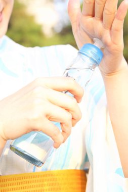 Geleneksel elbise giymiş, elinde su şişesi olan güzel Japon kadının portresi. 