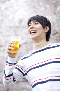 Parkta bira tutan genç Asyalı adam. 