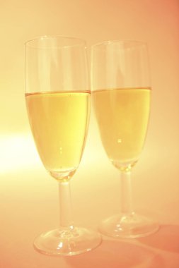 Parlak sarı arka planda iki kadeh şarap. 