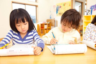 Anaokulunda resim çizen küçük Asyalı çocuklar.