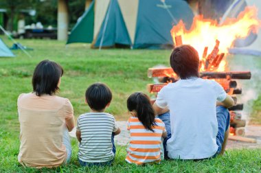 Asyalı dört kişilik aile kamp ateşinde dinleniyor.
