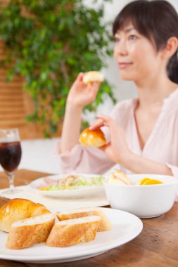 Kadın kahvaltıda ekmek ve salata yiyor.