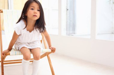 Asyalı kız bir sandalyede oturuyor