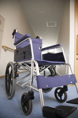 Boş mavi tekerlekli sandalye. Parlak hastane koridorunda oturuyor.