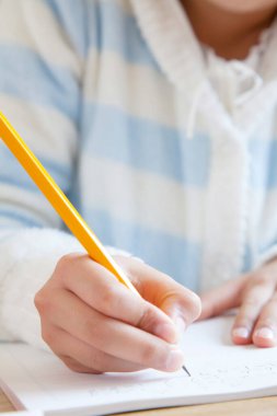 Küçük çocuk kurşun kalemle yazıyor. Görüntüyü kapat. 