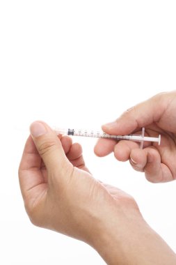 Adamın elleri beyaz arka planda bir şırınga tutuyor. 