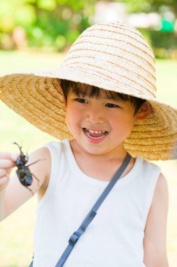 Hasır şapka takan gülümseyen çocuk.