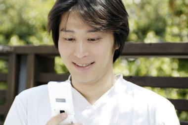 Yaz parkında cep telefonlu Japon bir gencin portresi.