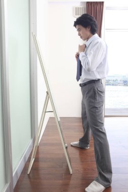 Genç adam aynanın karşısında duruyor. 