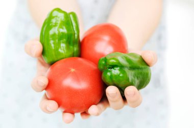 Taze domates ve yeşil biber tutan eller.