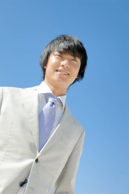 Gökyüzü arka planında Asyalı iş adamı 