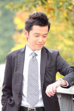 Takım elbiseli ve kravatlı bir adam saatine bakıyor.