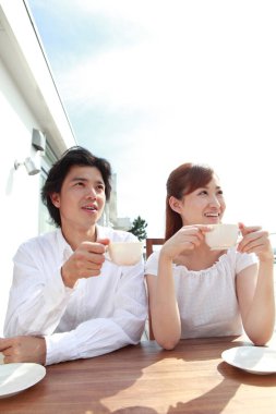 Genç çift balkonda kahvaltı yapıyor.