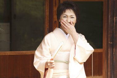 Katlanan yelpazeli güzel, olgun bir Japon kadın Anthwa 'da oturuyor.