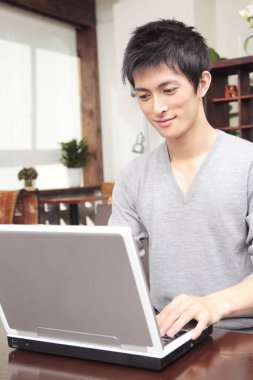 Kafede dizüstü bilgisayarda çalışan yakışıklı Asyalı adam.