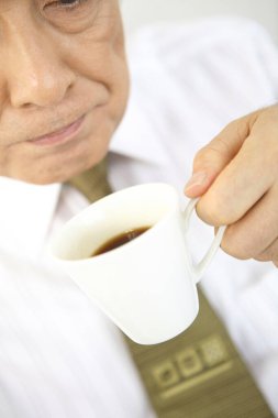 Asya 'lı kıdemli iş adamı elinde çay tutuyor.