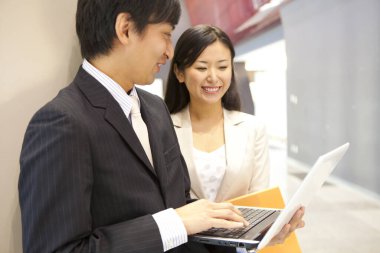 Genç Asyalı iş adamları modern ofiste dizüstü bilgisayarla çalışıyorlar.