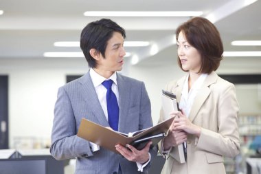 Bir erkek ve bir kadın ofiste duruyor. 