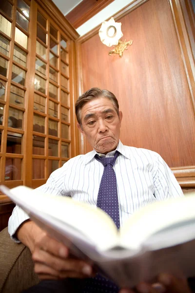 mature businessman reading book in room