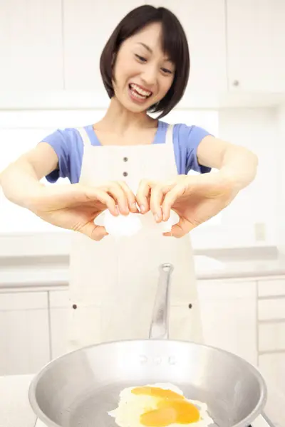 beautiful Asian housewife cooking in kitchen