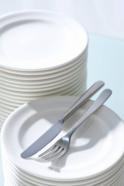 Masada temiz beyaz tabak ve çatal bıçak takımı var.