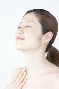 Güzel Japon kadın kendi yüz masajını yapıyor, beyaz arka planda yakın plan portresi. 