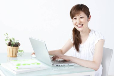 Genç Asyalı kadın evde dizüstü bilgisayar kullanıyor.