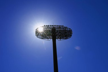 Mavi gökyüzüne karşı futbol stadyumunda lambalar