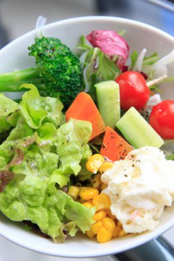 Karışık sebze salatası ve beyaz masada taze sebzeler.