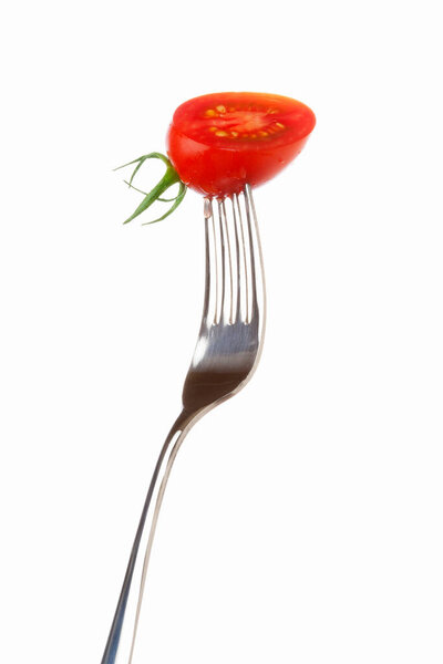 fresh ripe tomato in fork isolated on white background